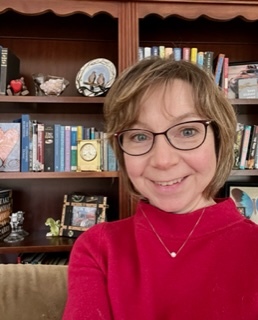 image of the author, a woman with medium length hair and glasses wearing a red sweater