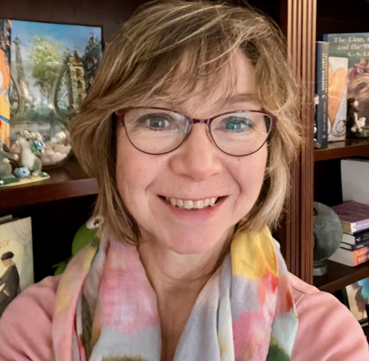 image of the author, a woman with medium length hair and glasses wearing a red sweater