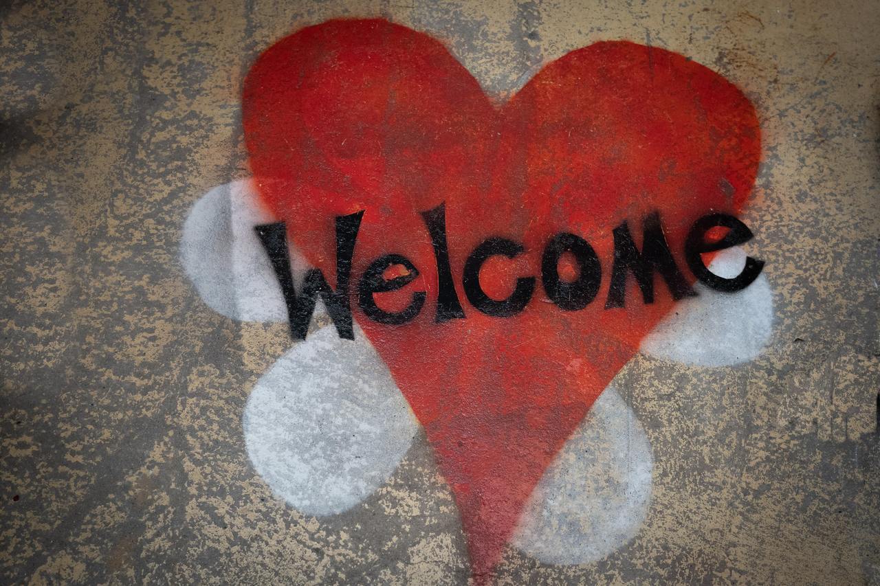 image of a red heart superimposed over a white six petaled flower with the word Welcome written on it.